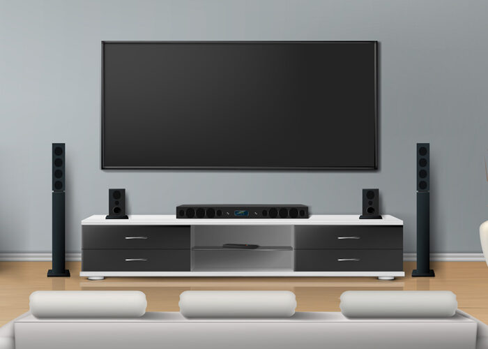 Beautiful living room with big flat screen TV on flat gray wall, entertainment cabinet with modern home theater speaker system with white sofa for watching movies.